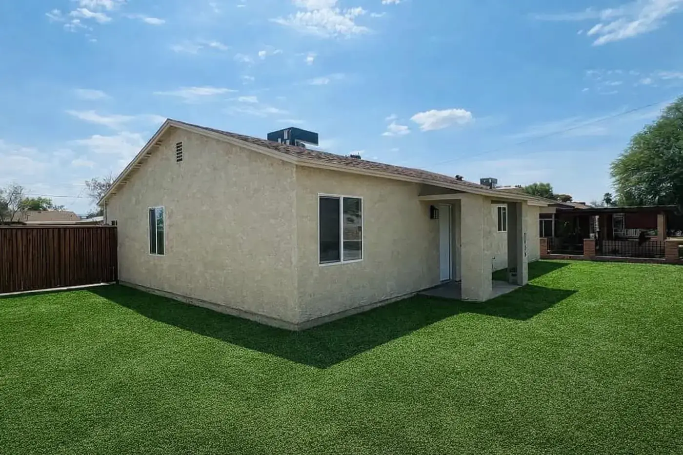 Rear three-quarter view of the finished casita with a tile roof, covered entry and turf lawn.
