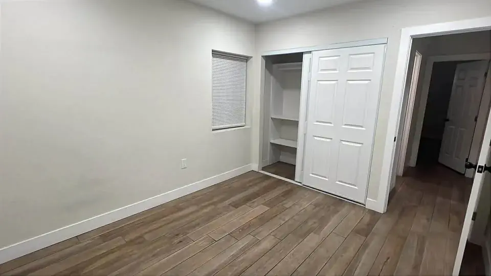 Bedroom with a built-in sliding-door closet and wood-look tile flooring.