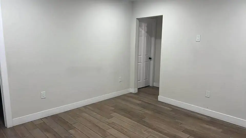 Empty third bedroom with a doorway to the hall and wood-look tile flooring.