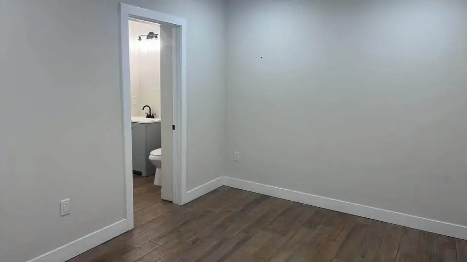 Bedroom with an open door revealing an en-suite bathroom with vanity and toilet.