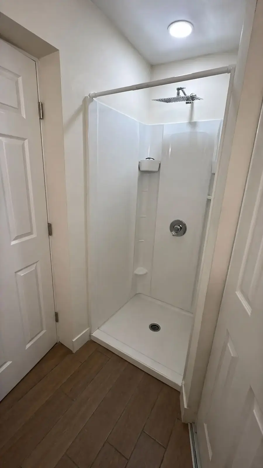 White walk-in shower enclosure with a square rain shower head.
