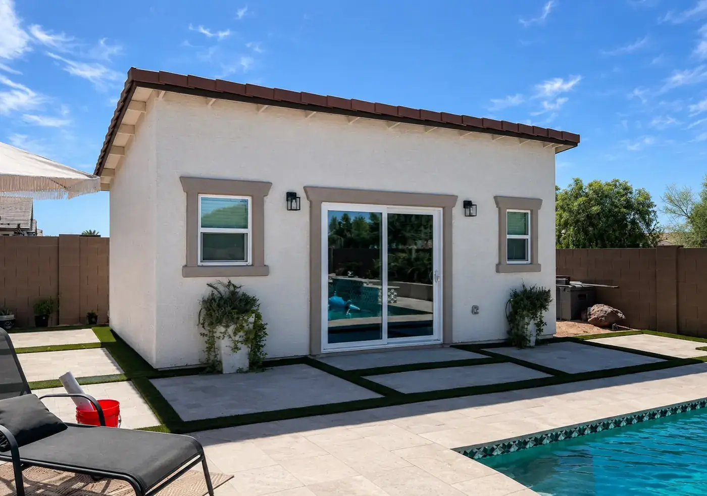 The finished 270 square foot pool lounge casita seen from the pool deck, with a sliding glass door and tile roof.