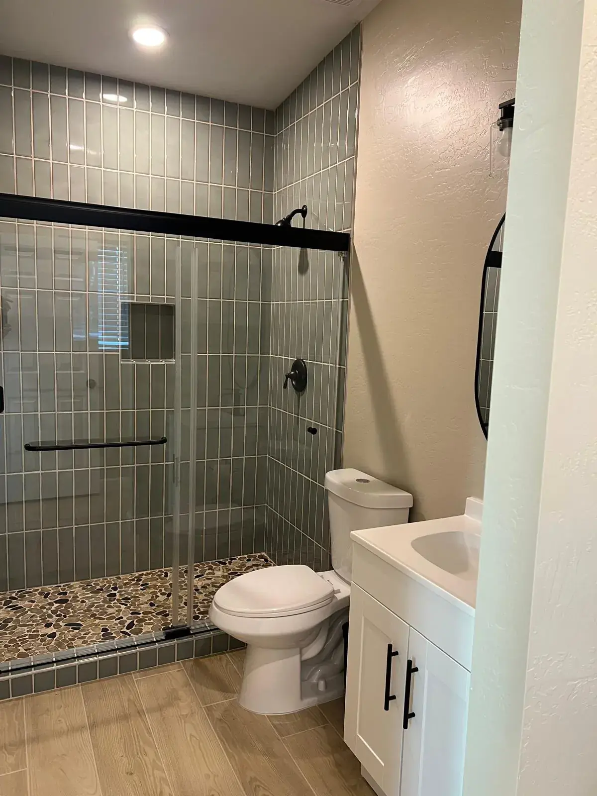 Finished bathroom with a glass shower enclosure, toilet and white vanity.