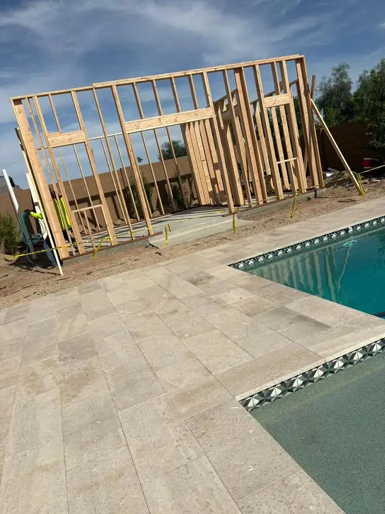 Timber wall framing standing on a slab next to the pool.