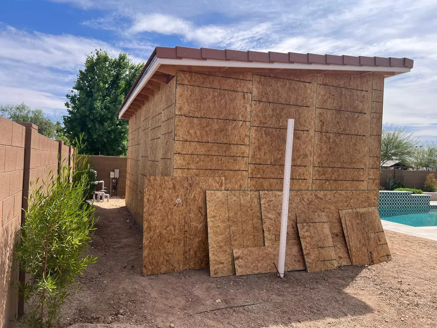 Rear of the sheathed casita with utility lines running along the block wall.